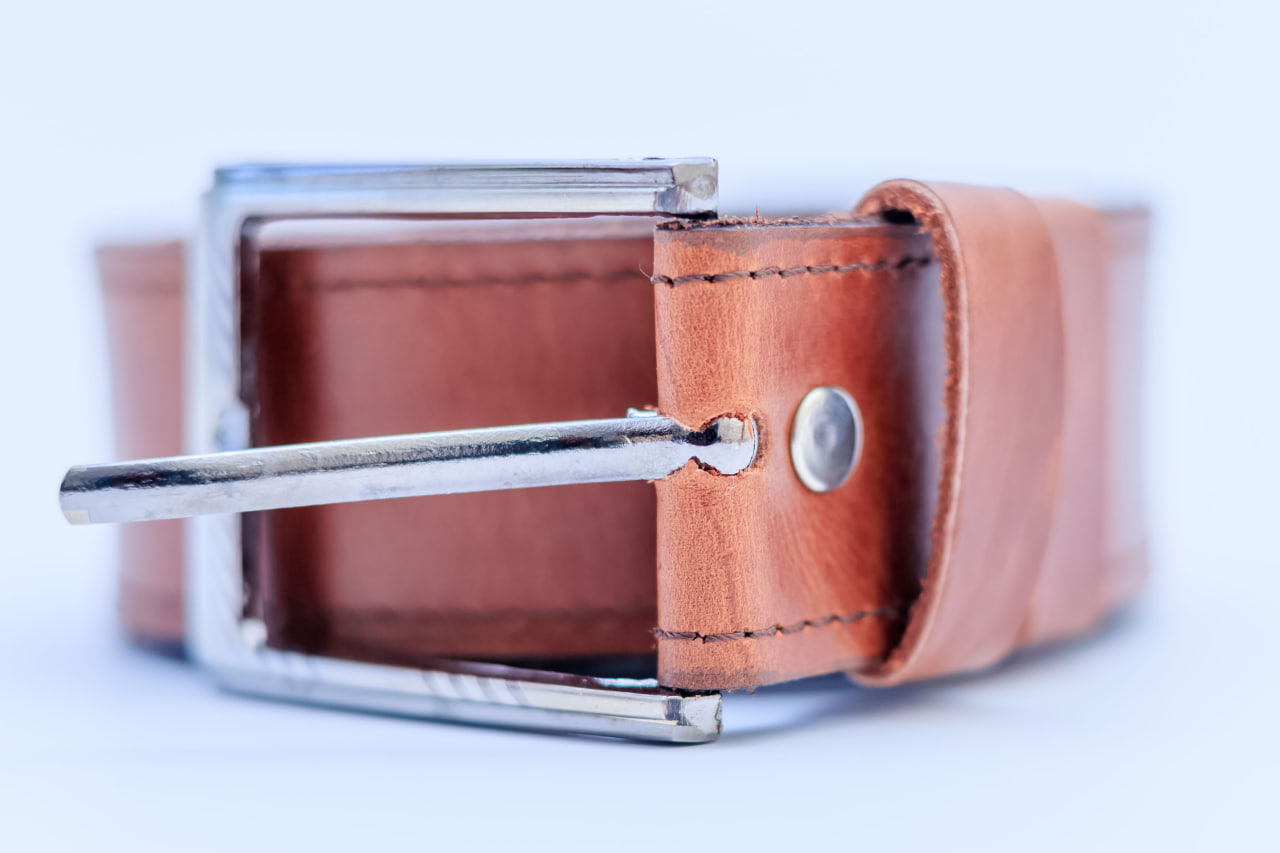 Desk with leather desk pad, walnut desk organizer, wireless keyboard and mouse, and porcelain mug.