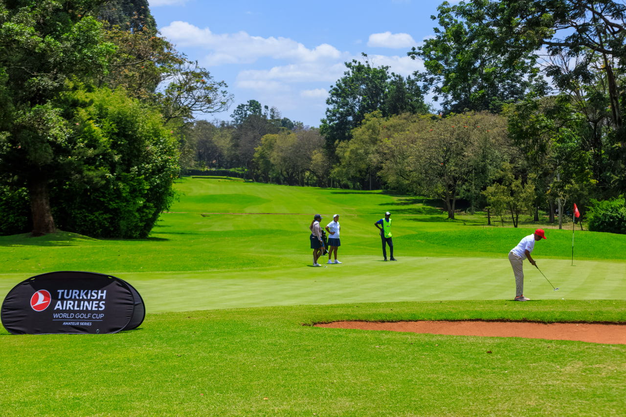 Desk with leather desk pad, walnut desk organizer, wireless keyboard and mouse, and porcelain mug.