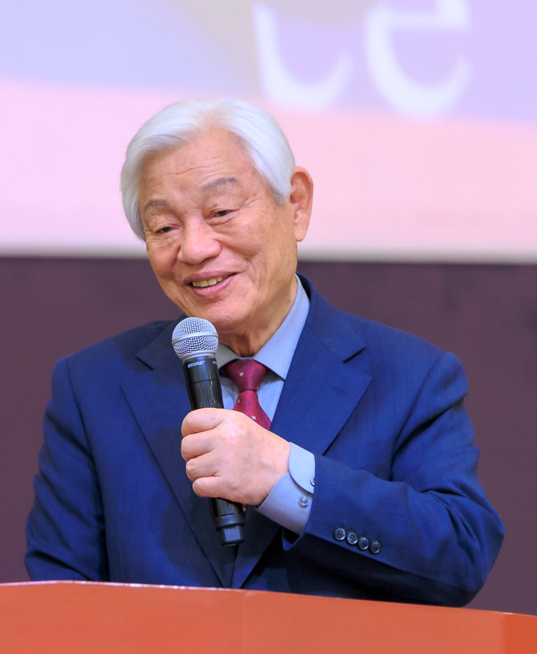 Desk with leather desk pad, walnut desk organizer, wireless keyboard and mouse, and porcelain mug.