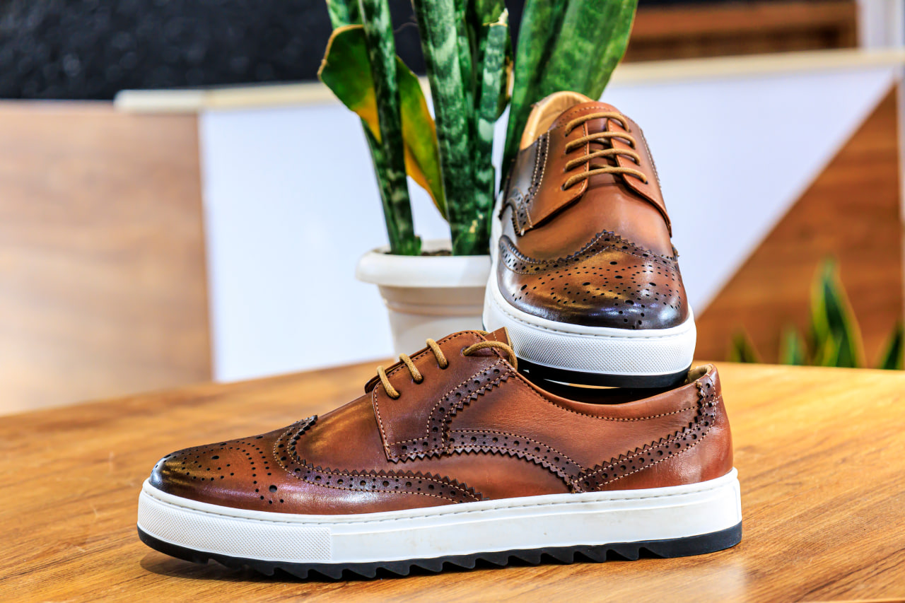 Kettle spout pouring boiling water into coffee grounds in pour-over mug.