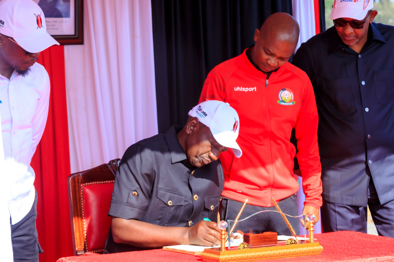 Desk with leather desk pad, walnut desk organizer, wireless keyboard and mouse, and porcelain mug.