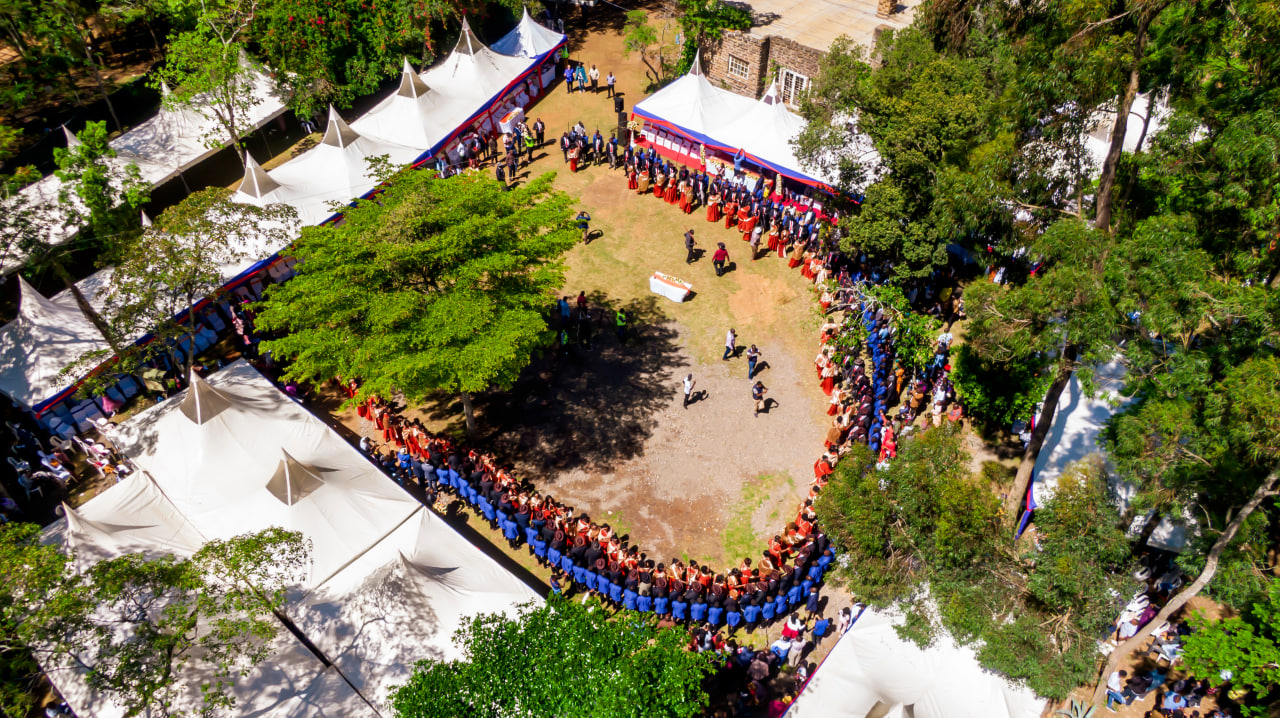 Desk with leather desk pad, walnut desk organizer, wireless keyboard and mouse, and porcelain mug.