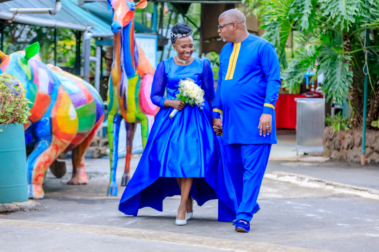Desk with leather desk pad, walnut desk organizer, wireless keyboard and mouse, and porcelain mug.