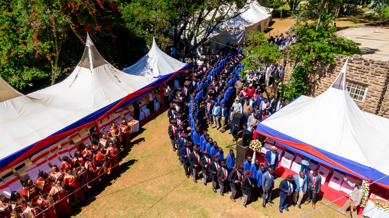 Desk with leather desk pad, walnut desk organizer, wireless keyboard and mouse, and porcelain mug.