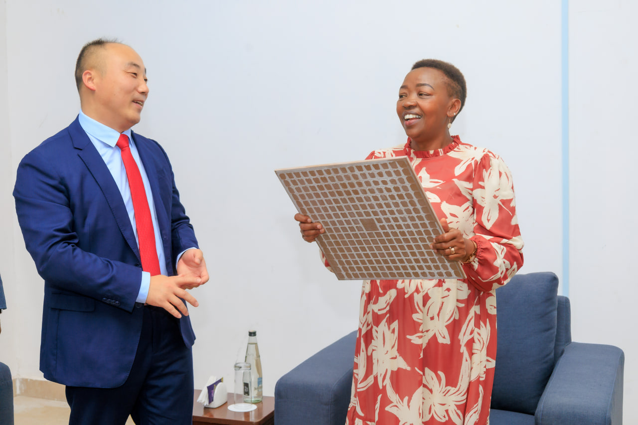 Desk with leather desk pad, walnut desk organizer, wireless keyboard and mouse, and porcelain mug.