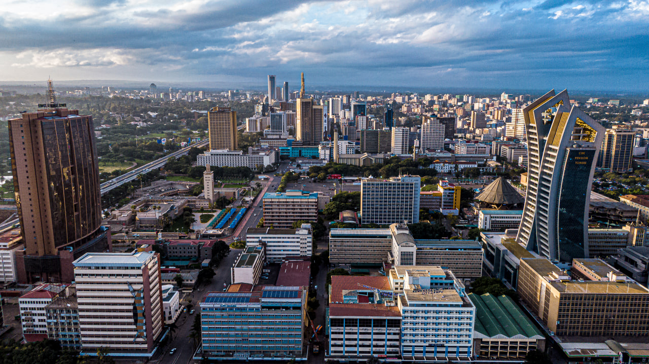 Desk with leather desk pad, walnut desk organizer, wireless keyboard and mouse, and porcelain mug.