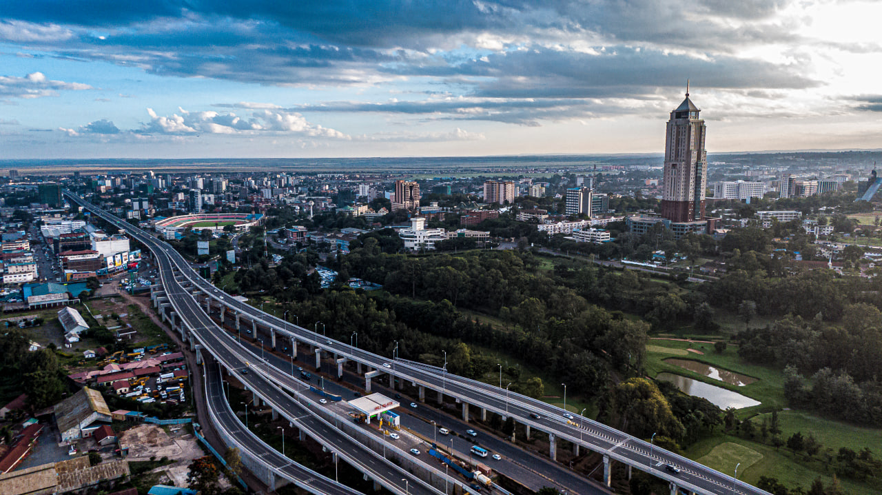 Desk with leather desk pad, walnut desk organizer, wireless keyboard and mouse, and porcelain mug.