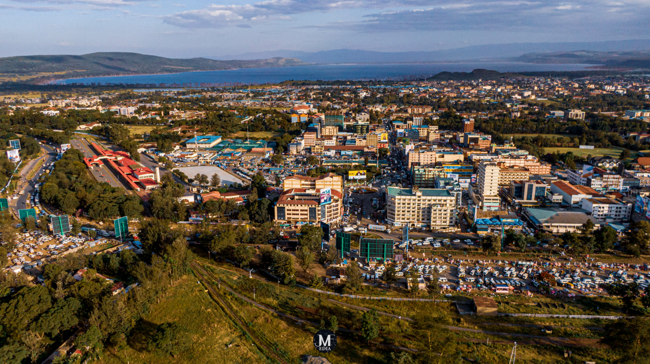 Desk with leather desk pad, walnut desk organizer, wireless keyboard and mouse, and porcelain mug.
