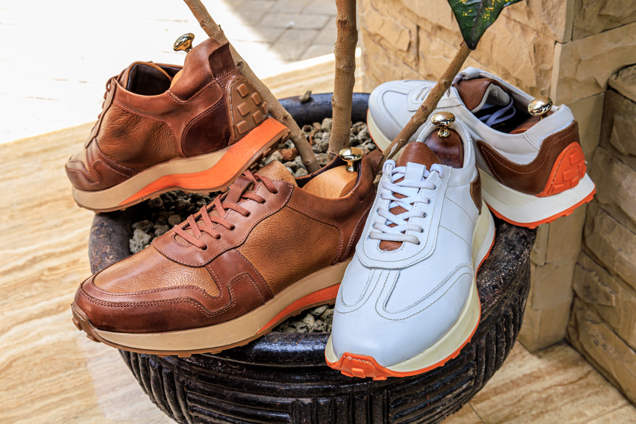 Desk with leather desk pad, walnut desk organizer, wireless keyboard and mouse, and porcelain mug.
